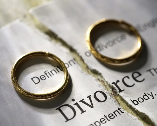 2 wedding rings on a table with a divorce paper behind