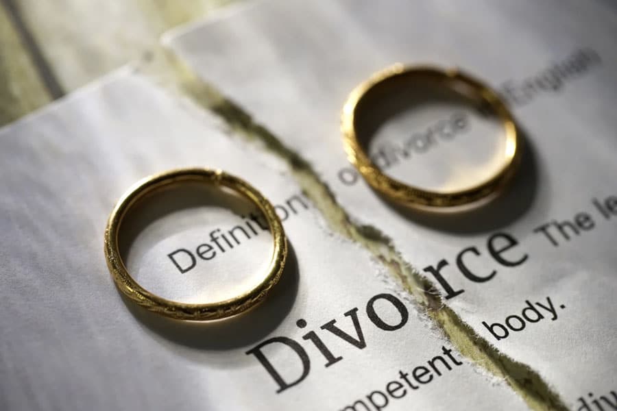 2 wedding rings on a table with a divorce paper behind